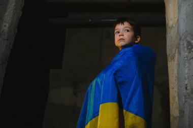 Ukrayna bayrağına sarılı üzgün bir Ukraynalı çocuk Mariupol ya da Kiev 'deki bir sığınakta bombalardan saklanıyor. Rusya 'nın saldırganlığı. Ukrayna ve 2022 'deki savaş..