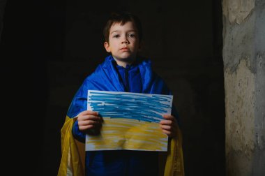 Ukrayna bayrağına sarılı üzgün bir Ukraynalı çocuk Mariupol ya da Kiev 'deki bir sığınakta bombalardan saklanıyor. Rusya 'nın saldırganlığı. Ukrayna ve 2022 'deki savaş..