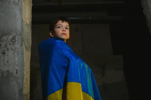 Smutny Ukraiński Chłopiec Zawinięty Ukraińską Flagę Ukrywający Się Przed Bombardowaniami — Zdjęcie stockowe