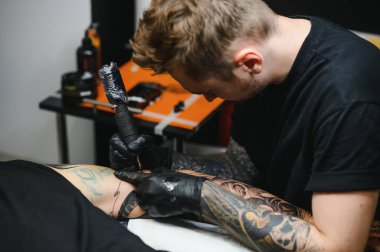 Kolunda makine dövmesi olan dövmeci tasarım, sanat ve tasarım konsepti çizilmiş.