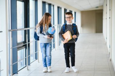 Okul koridorunda elinde kitaplarla gülümseyen çocukların portresi..