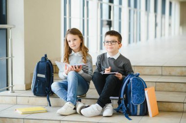 Okul çocukları koridorda birlikte kitap okuyorlar. Eğitim kavramı.