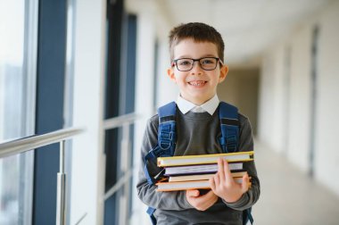 Gözlüklü, okul çantalı ve elinde kitapla mutlu, zeki bir çocuk. Okula ilk gelişim. Okula geri dön..