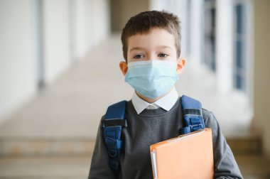 Yüzünde koruyucu maske olan bir öğrenci. Coronavirüs salgını. İlaç maskesi takan bir çocuk. Coronavirus konsepti. Koronavirüs salgını için yüz maskesi. Virüse karşı yüz maskesi, hastalık, salgın.