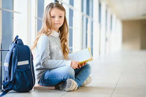 一个漂亮的金发女学生 手里拿着许多彩色的笔记和书籍 聪明的少女站在国际学校的走廊上 对着镜头微笑 — 图库照片