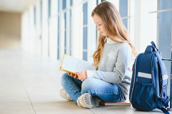 Ένα Όμορφο Κοριτσάκι Κάθεται Στο Πάτωμα Του Σχολείου Και Διαβάζει — Φωτογραφία Αρχείου