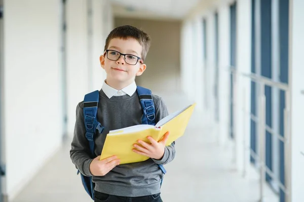 学校では通学用のかばんと本を持っている少年 教育の概念 学校に戻る 小学生は授業に行く バックパック付きのスタイリッシュな男の子 勉強の準備ができている少年 — ストック写真