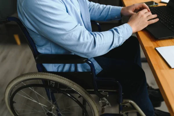 Young happy entrepreneur in wheelchair working on laptop at home.