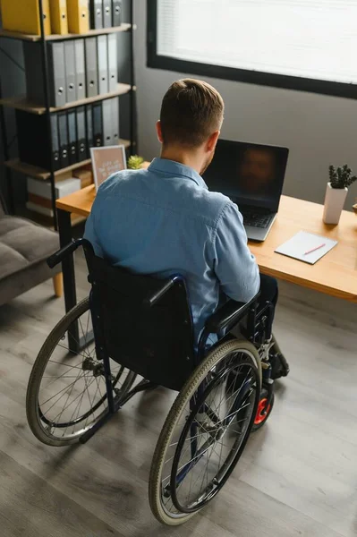 Handicapped Businessman Sitting On Wheelchair And Using Computer In Office