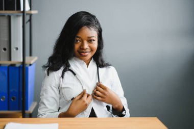 Kendine güvenen Afrikalı doktor kadın doktor hasta notları hastane koridorlarının arka planında izole edilmiş. Pozitif yüz ifadesi