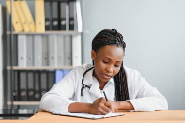 Kendine güvenen Afrikalı doktor kadın doktor hasta notları hastane koridorlarının arka planında izole edilmiş. Pozitif yüz ifadesi