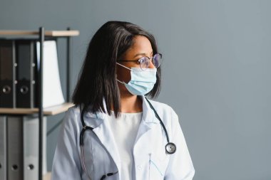 Tıp, meslek ve sağlık konsepti - koruyucu maskeli Afrikalı kadın doktor veya bilim adamına yakın çekim.