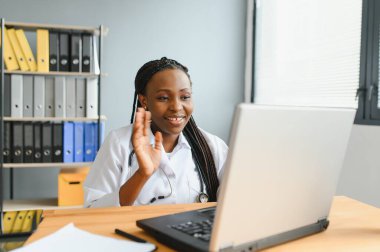 Afrikalı kadın doktor çevrimiçi teletıp görüntülü arama hastası yapıyor. Afro-Amerikalı siyahi kadın terapist uzaktan video konferans sohbetinde kamerayla konuşuyor. Web kamerası görüntüsü, yüz görüntüsü
