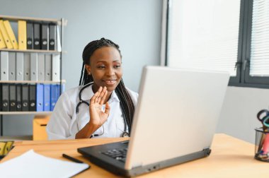 Afrikalı kadın doktor çevrimiçi teletıp görüntülü arama hastası yapıyor. Afro-Amerikalı siyahi kadın terapist uzaktan video konferans sohbetinde kamerayla konuşuyor. Web kamerası görüntüsü, yüz görüntüsü