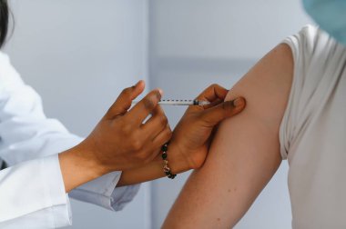 Kadın Afrikalı doktor bir hastaya iğne yapıyor.