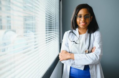 Gülümseyen genç Hintli kadın doktor klinikte beyaz önlük giyiyor. Mutlu güzel Hindistan sağlık hizmetleri uzmanı doktor, terapist, vesikalık portre.