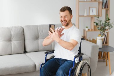 Evinde tekerlekli sandalyede oturan düşünceli genç bir adam.
