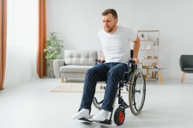 Evde sakat bir adam tekerlekli sandalyede ayağa kalkmaya çalışıyor. Yaralanmalardan ve araba kazalarından sonra rehabilitasyon kavramı.