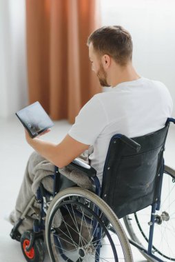 Tekerlekli sandalyedeki modern engelli adamın video çağrısı var.