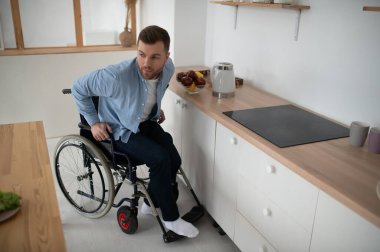 Tekerlekli sandalyedeki engelli genç adam Mutfakta Yemek Hazırlıyor