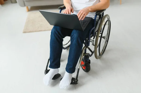 坐在轮椅上的人在客厅的笔记本电脑上工作 — 图库照片