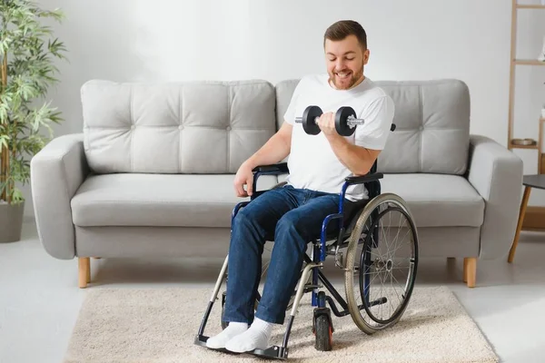 残疾人 残疾人运动 男性在轮椅与哑铃在手 手里拿着哑铃的男人 父亲残疾人做斑点 在公寓里运动 健康理念 健康的生活方式 — 图库照片