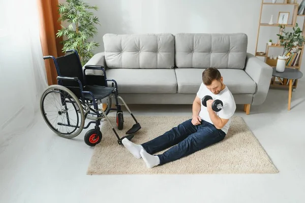 Man Disabled. Sports for Disabled. Male in Wheelchair with Dumbbells in Hands. Man with Dumbbells in Hands. Father Disabled Do Spotting. Sport at Apartment. Health Concept. Healthy Lifestyle.