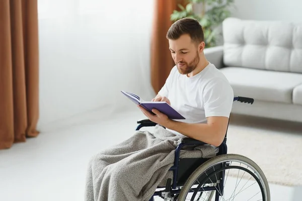 Mężczyzna Wózku Inwalidzkim Czyta Książkę Domu — Zdjęcie stockowe
