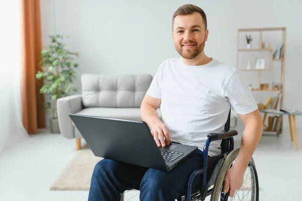 坐在轮椅上 坐在笔记本电脑上 脸上挂着微笑的残疾男性形象 有特殊需要的青年工人 自由职业者和残疾人概念 — 图库照片