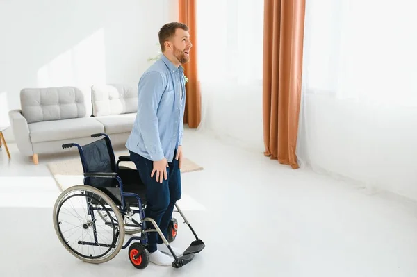 Niepełnosprawny Młody Facet Próbuje Wstać Wózka Inwalidzkiego Domu Skopiować Przestrzeń — Zdjęcie stockowe