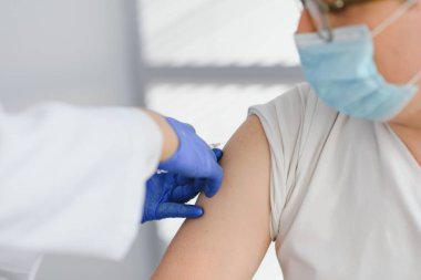 Koluna grip aşısı, koronavirüs aşısı, covid-19 aşısı aşısı aşısı yapılan bir hastanın omzuna aşı yapan bir doktor hastaya yakından bakın..