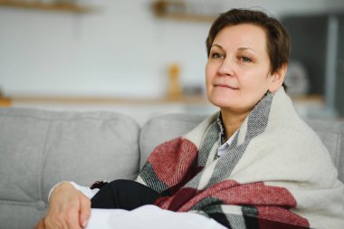 Olgun Kadın. Evdeki koltukta oturan sağlıklı, orta yaşlı, güzel bir kadın. Güzellik ve Rahatlık Konsepti.
