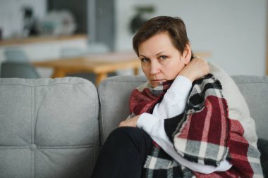 Evdeki kanepede ekoseli yaşlı bir kadının portresi.