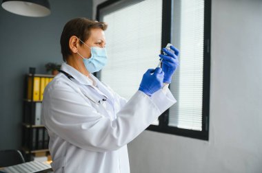 Doktor üniformalı kadın doktor ya da bilim adamlarının yakından incelediği yüz maskesi takan laboratuarda sıvı aşı şişesi, koronavirüs ya da COVID-19 konsepti tutan kişi..