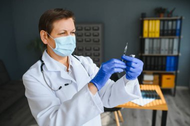 Doktor üniformalı kadın doktor ya da bilim adamlarının yakından incelediği yüz maskesi takan laboratuarda sıvı aşı şişesi, koronavirüs ya da COVID-19 konsepti tutan kişi..
