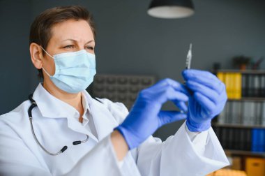 Araştırmacıların elinde COVID-19 aşısı, kadın doktor Coronavirus tedavisi aşısı için şırınga ve şişe tutuyor. Salgın sırasında korona virüsü tedavisi, enjeksiyon, iğne ve klinik deney kavramı.
