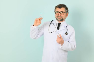 Koronavirüse karşı aşı. COVID-19 aşıları test ediliyor. Erkek bir doktor şırıngaya mavi arka planda COVID-19 aşısı dolduruyor. Doktorun elleri şırıngayı yakın çekimde tutuyor..