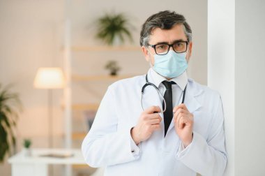 Beyaz önlük, steteskop, gözlük ve yüz maskesi takan olgun, yaşlı bir doktor. Sağlık personeli sağlık koruma konsepti. Portre