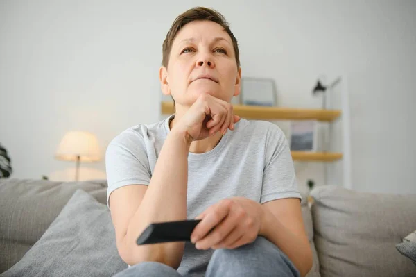 Middle Aged Woman Sitting Sofa Turning Remote Control — стоковое фото