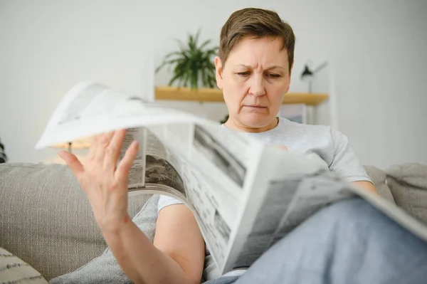 女人坐在家里看报纸 — 图库照片