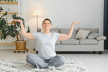 Orta yaşlı bir kadın evde yoga yapıyor esneme ve sağlıklı olma için.