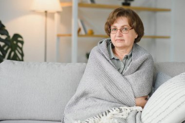 evde bir kanepede oturan rahat büyükanne