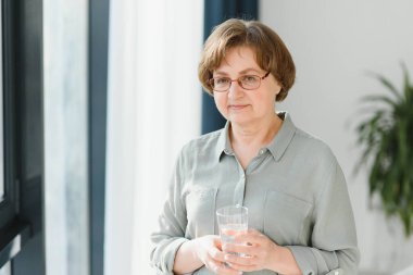 Elinde bir bardak su tutan yaşlı bir kadın. Emeklilik kavramı.