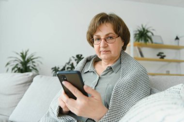 Yakışıklı büyükanne evde telefonla konuşuyor.