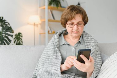 Yakışıklı büyükanne evde telefonla konuşuyor.