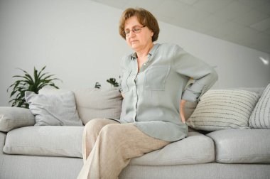 Olgun bir kadın yatakta oturuyor ve sırtına dokunuyor. Radkülit ve acı..