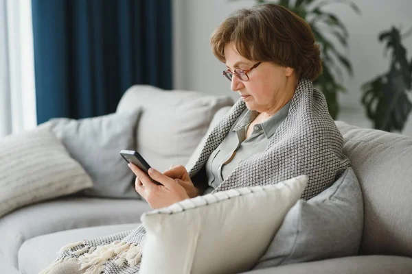 Yakışıklı büyükanne evde telefonla konuşuyor.