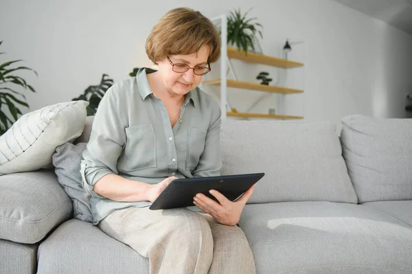 Kanepedeki dijital tabletine bakıp gülen son sınıf öğrencisi kadın..