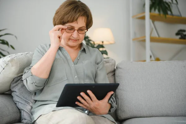 Kanepedeki dijital tabletine bakıp gülen son sınıf öğrencisi kadın..