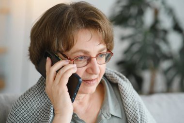 Yakışıklı büyükanne evde telefonla konuşuyor.